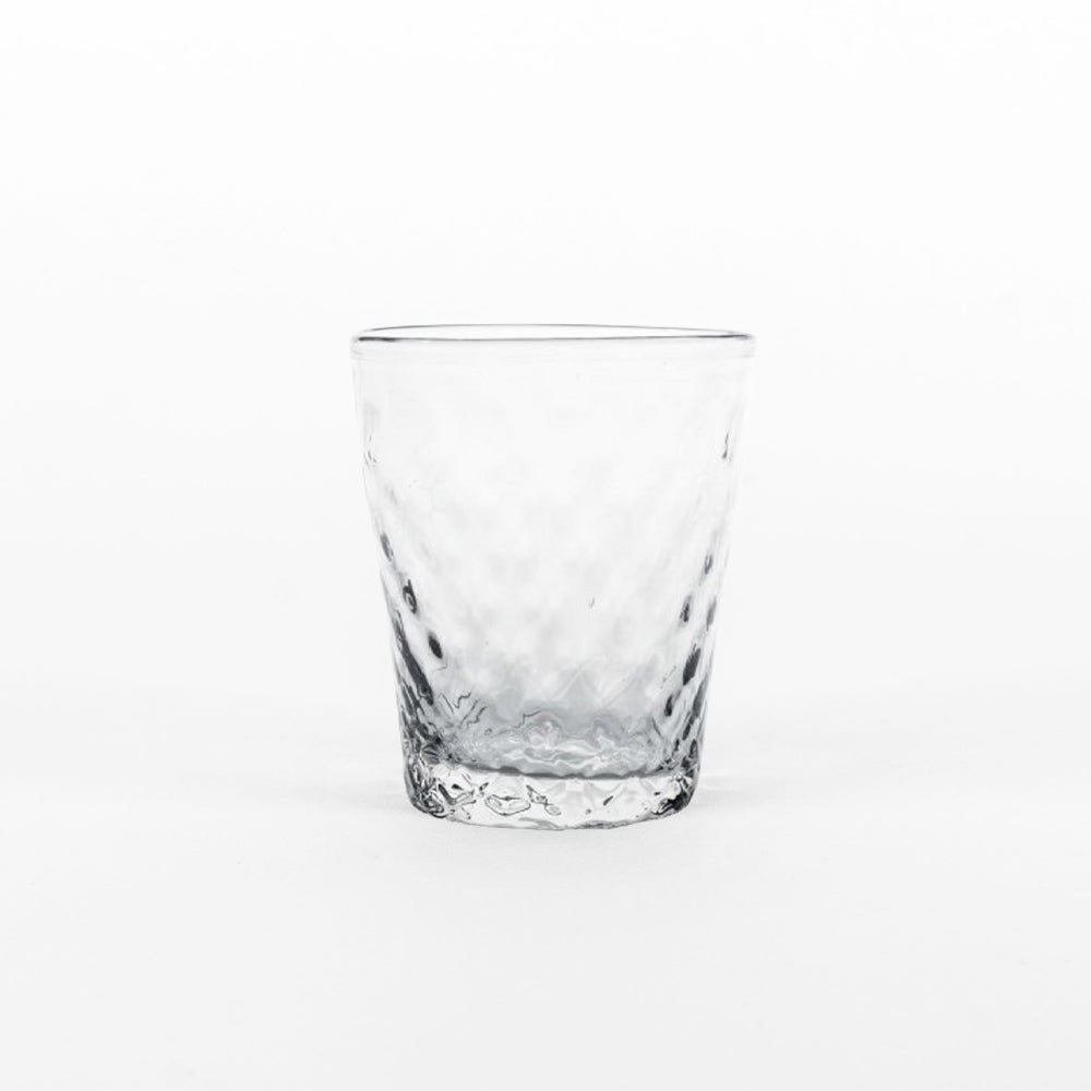 verre transparent en verre avec faceted surface et csurical shape, placed sur uniform fsurd blanc