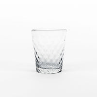 verre transparent en verre avec faceted surface et csurical shape, placed sur uniform fsurd blanc