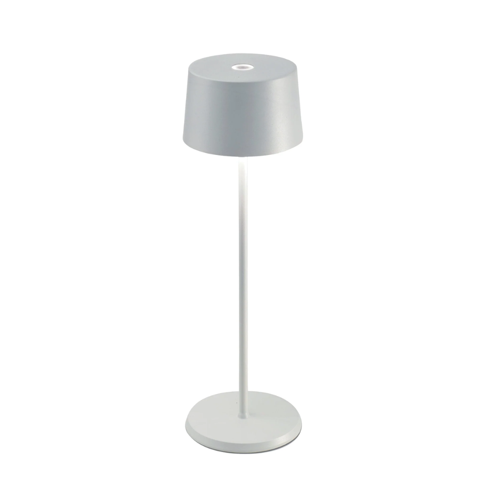 Lampada da tavolo grigia con base e stelo bianchi, struttura cilindrica smussata e materiale apparente plastico o metallico.