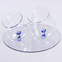Two transparent glass glasses with round blue base resting on a white reflective transparent plate.
