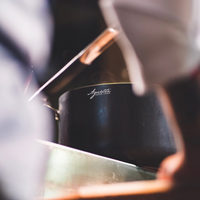 Zwarte pan met lange steel, Agnelli-logo in wit gegraveerd, op kookplaat in keuken met lichte vervaging eromheen