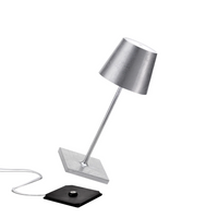 lampada da tavolo cromata con paralume a forma conica, base quadrata, interruttore nero e cavo bianco, sfondo bianco
