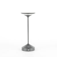 lampada da tavolo grigia opaca con base conica, stelo sottile e diffusore piatto a forma di disco, logo ab+ bianco sulla base