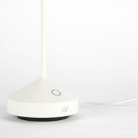 Base bianca di lampada con interruttore circolare grigio, stemma "ab+" e cavo di alimentazione su sfondo chiaro.