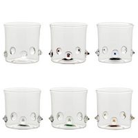 Sei bicchieri di vetro trasparente con decorazioni rotonde in rilievo di vari colori (bianco, rosso, blu, grigio, verde, arancione) su