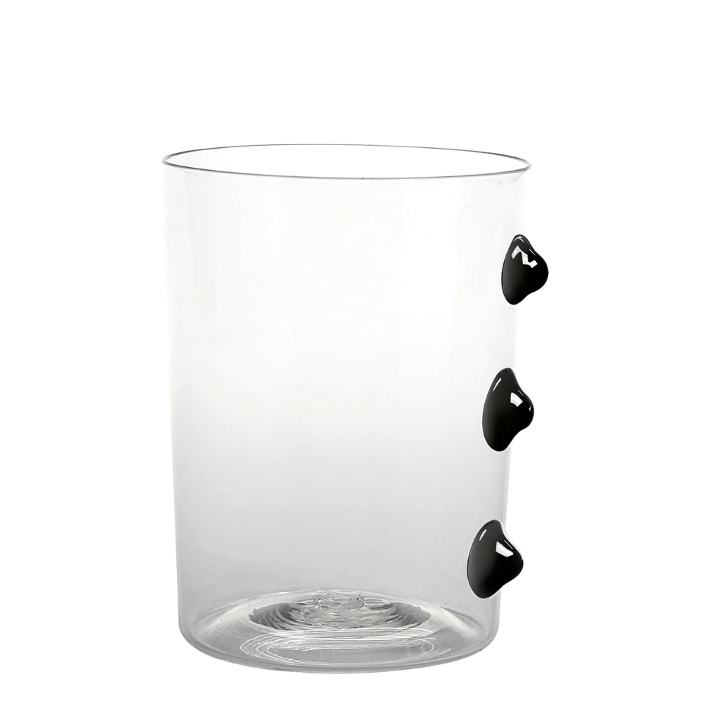 Verre transparent en verre avec trois décorations noires bombées sur le côté, fond blanc simple