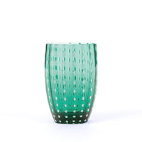 Transparent green glass tumbler with uniform white polka dot decorations, neutral white background.