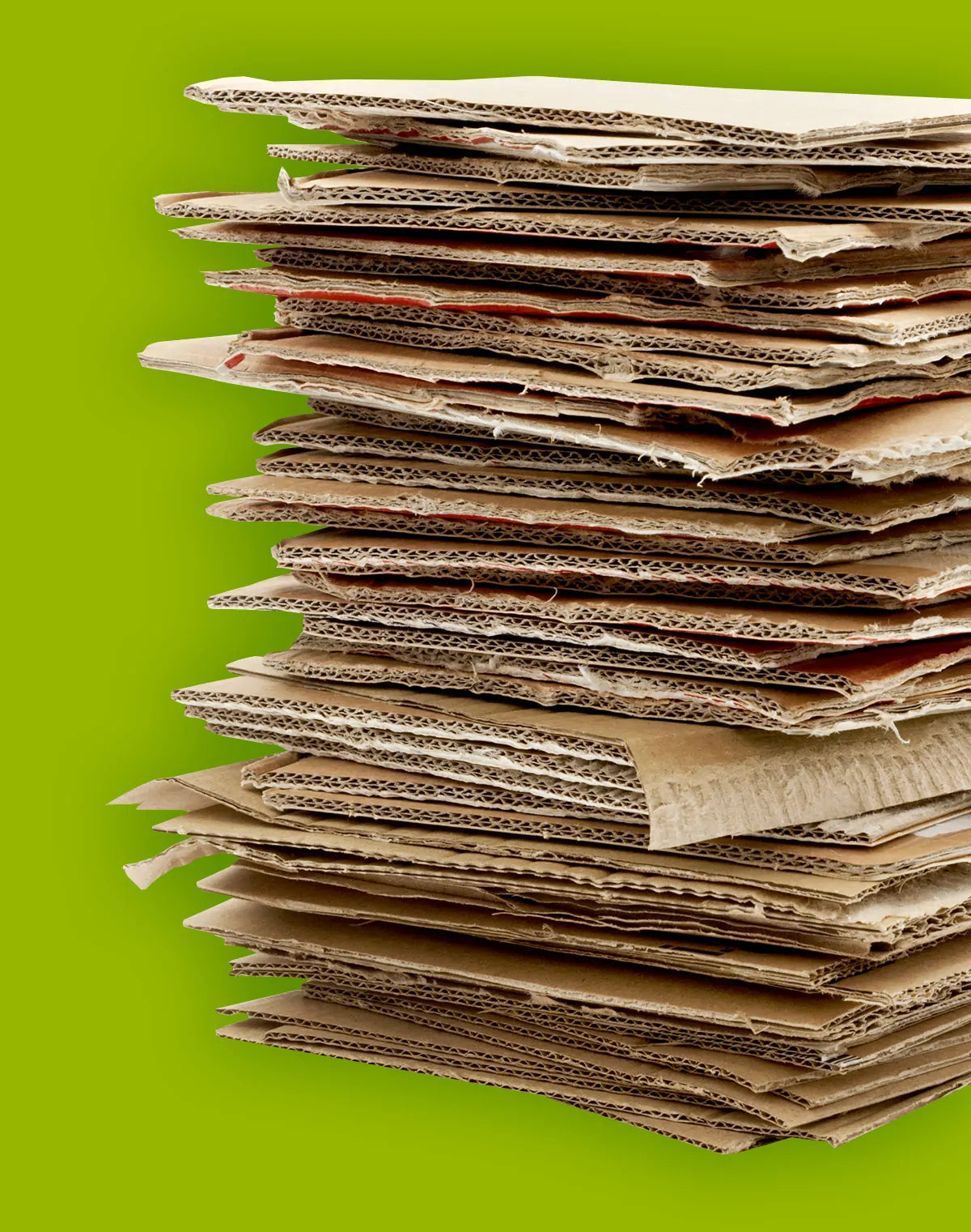 Pile de cartons ondulés marron clair disposés les uns sur les autres avec fond vert uniforme