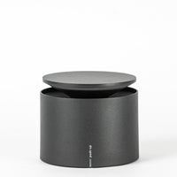 Matte black cylindrical object with flat lid, with "push-up" text on front.