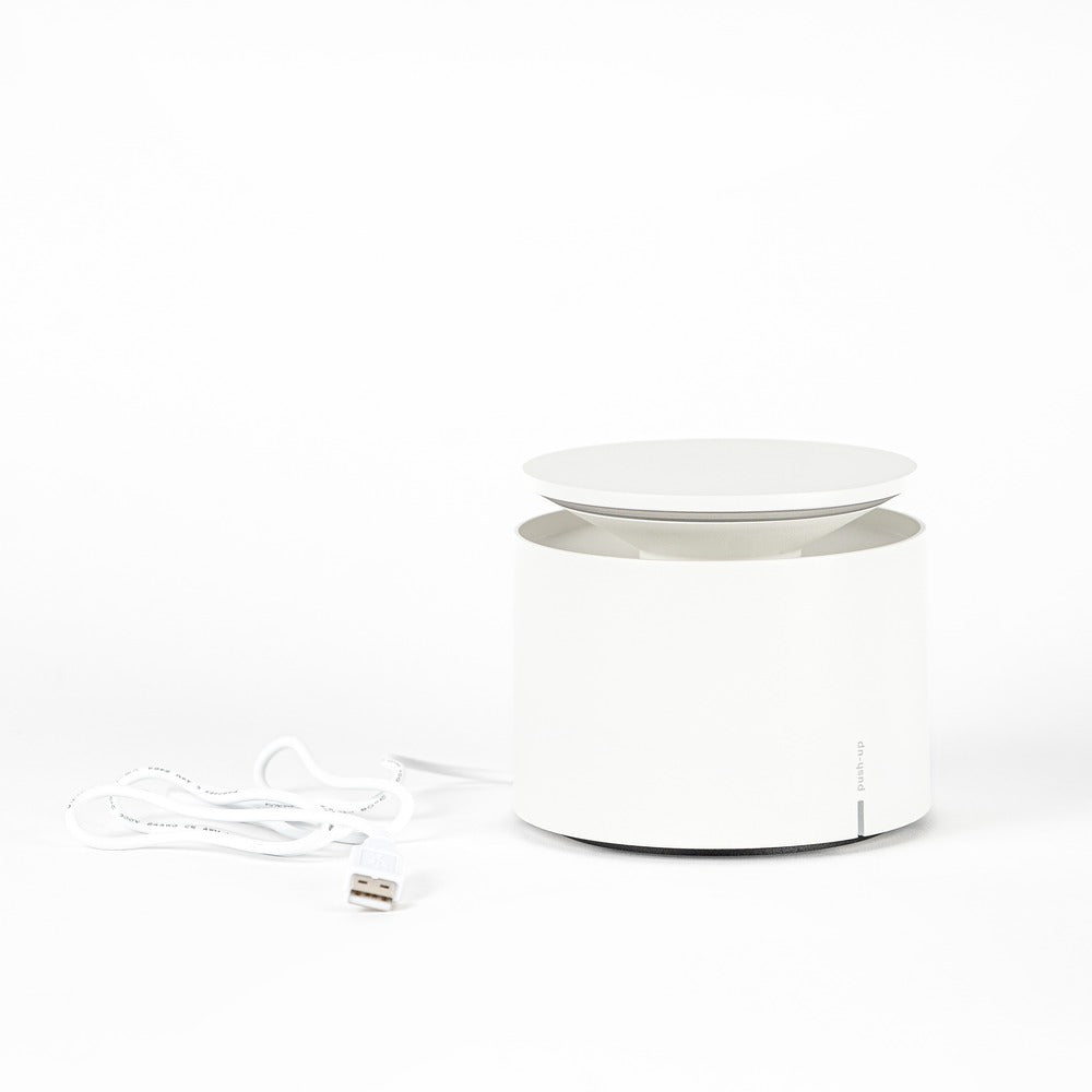 White cylindrical device with top platform, USB cable on the left on white background.