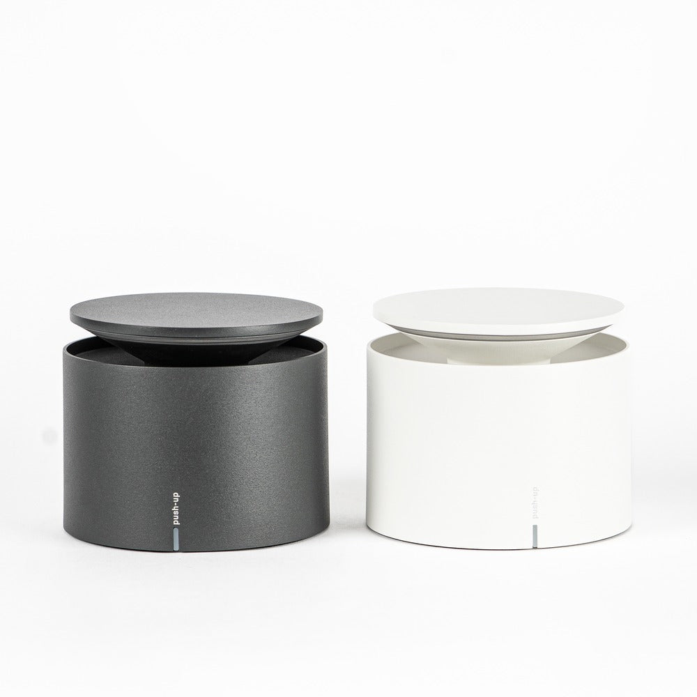 Two cylindrical containers, one black and one white, with flat lid, simple and modern on white background.