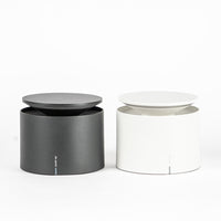 Two cylindrical containers, one black and one white, with flat lid, simple and modern on white background.