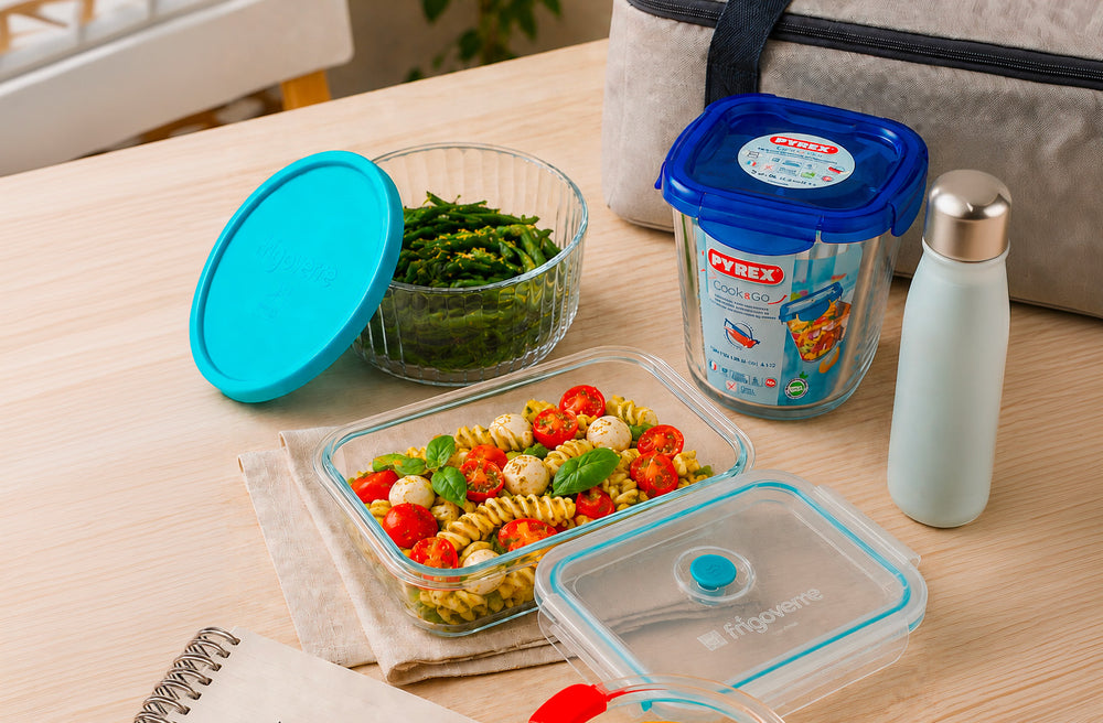 Contenitori per alimenti con insalata e ingredienti freschi su un tavolo.