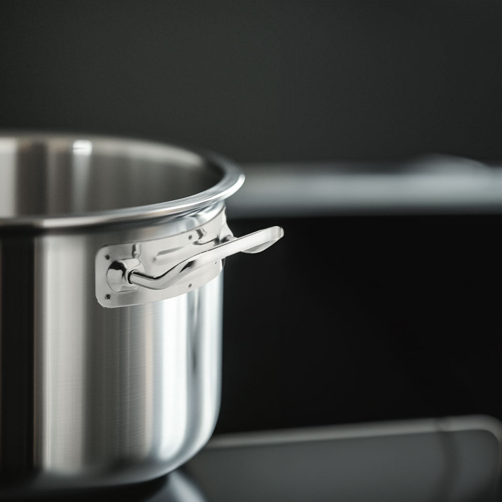 Glossy stainless steel pot with short handle, placed on black stovetop in dark kitchen setting.