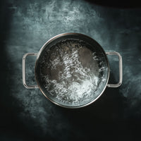 Casserole en acier inoxydable avec eau bouillante vue du dessus sur plan de travail sombre réfléchissant