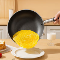 Padella antiaderente nera rotonda con manico metallico, mano che versa frittata gialla su piatto bianco in cucina con vetro di latte, pane