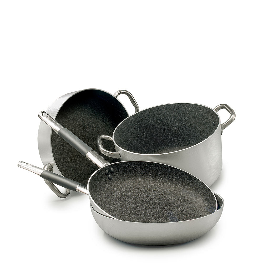 Set de ollas y sartenes de acero con interior antiadherente negro, mangos de metal y silicona gris, fondo blanco