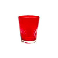 Bicchiere trasparente rosso in vetro con base chiara su sfondo bianco.