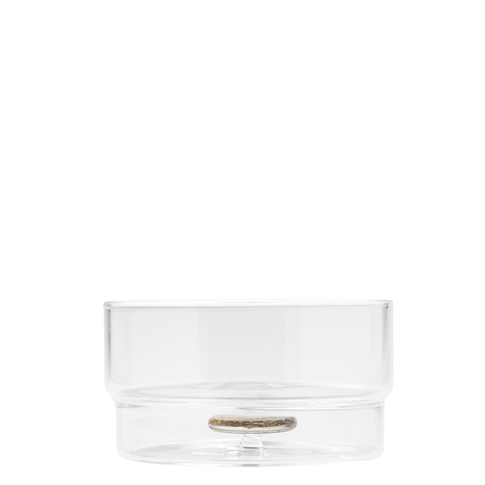 Transparent glass container with thin base and round bottom, with a colored circular object inside. White background.
