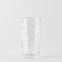 Transparentes Glas mit graviertem Blattmuster, dicker Basis, neutraler weißer Hintergrund.