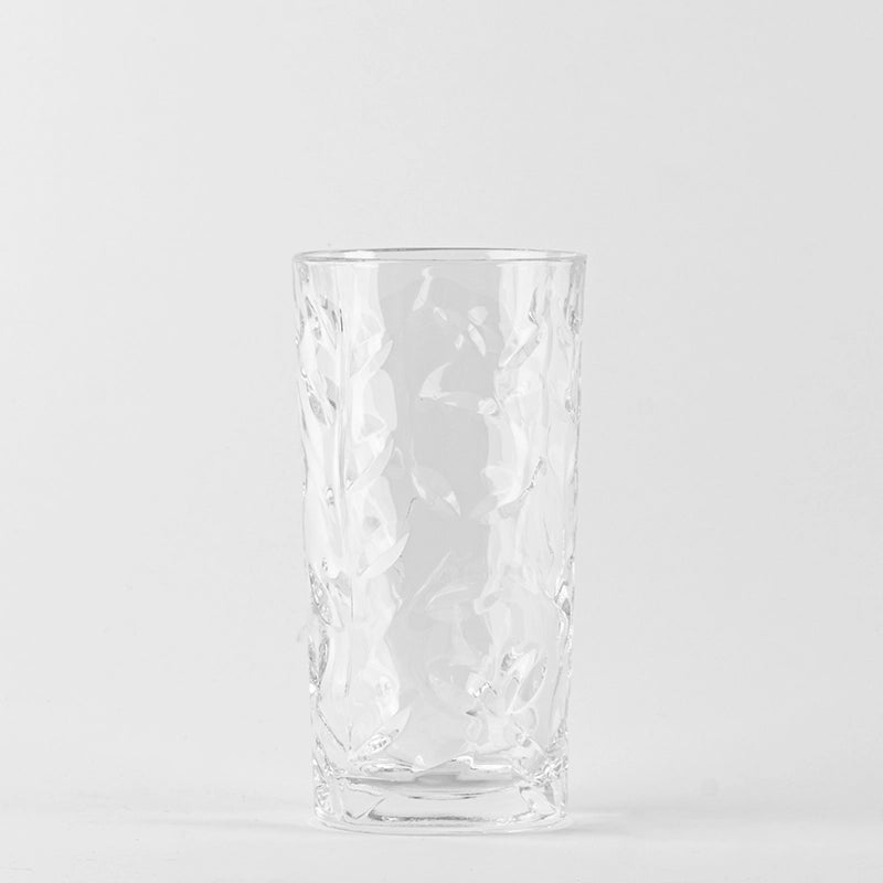 Transparentes Glas mit graviertem Blattmuster, dicker Basis, neutraler weißer Hintergrund.