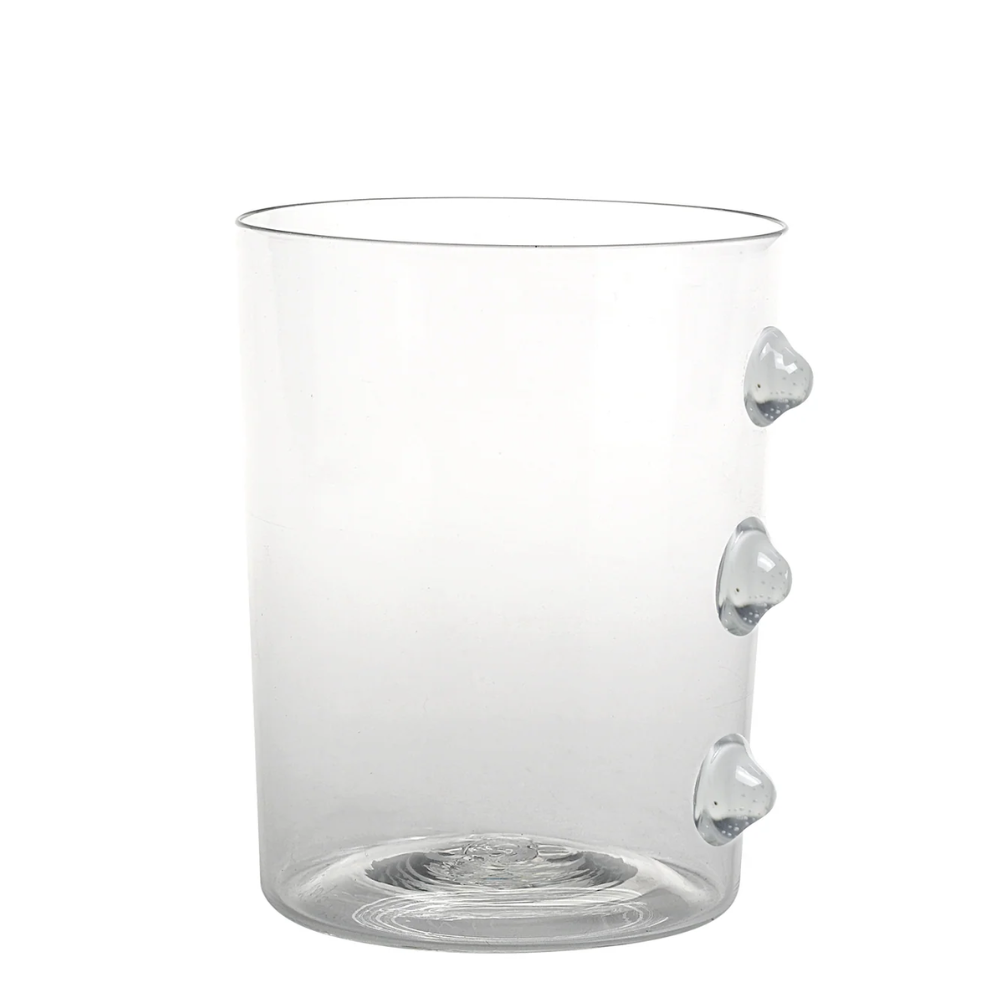 Verre transparent en verre avec trois protubérances rondes sur le côté droit, fond blanc.
