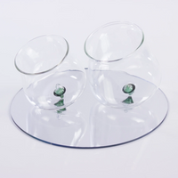 two transparent glass glasses with green decorative base placed on white reflective surface