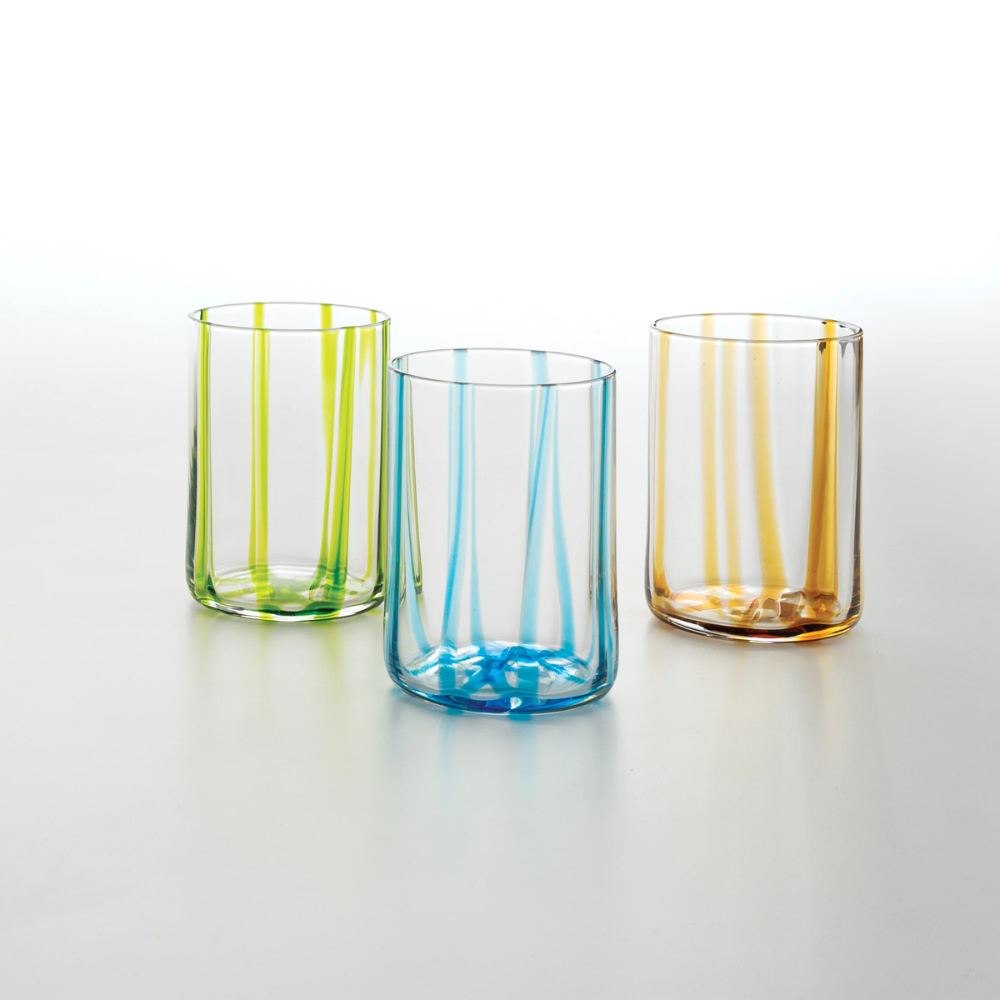 Tre bicchieri di vetro trasparente con strisce verticali colorate in verde, azzurro e arancione su sfondo bianco.