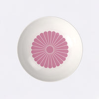 Piatto bianco con decorazione centrale rotonda di petali rosa su fondo chiaro, superficie liscia e lucente.